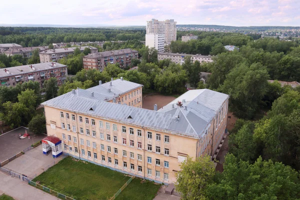 View of school building and residential buildings among trees — Stock Photo, Image