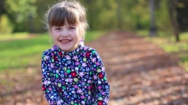 Güneşli sonbahar parkta güzel sevimli küçük kız güler