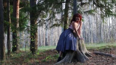 Güzel kız büyük güdük üzerinde oturur ve Rüzgar sonbahar ormandaki poz veriyor