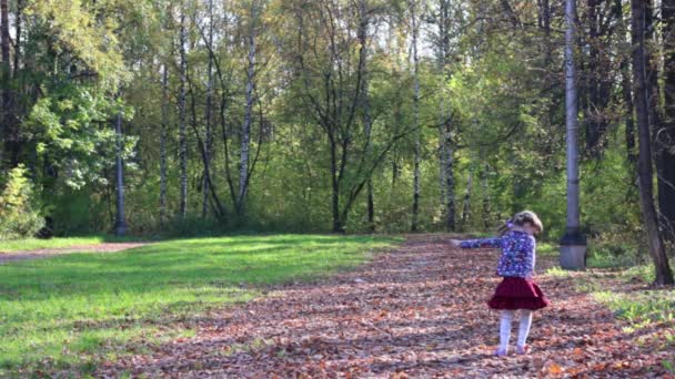 Vacker liten flicka i kjol snurrar i höst park — Stockvideo