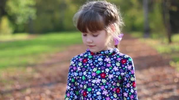 Belle petite fille parle et gesticule dans le parc ensoleillé d'automne 