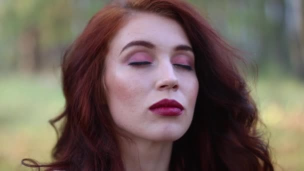 Крупним планом красива дівчина з закритими очима відкриваючи губи і очі в лісі — стокове відео