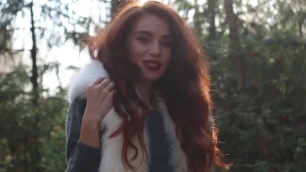 Pretty girl touches soft white fur on her shoulders in forest — Stock Video
