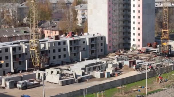 Вид сверху строительной площадки с краном и новым бетонным панельным зданием — стоковое видео