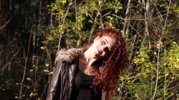 Hübsche junge Frau schüttelt an sonnigem Tag im Herbstwald ihre Haare — Stockvideo