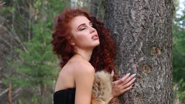 Pretty young woman poses as animal near tree in autumn forest at sunny day
