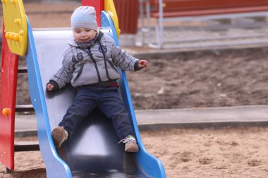 Yakışıklı çocuk gri slayt ve gülümser rides 