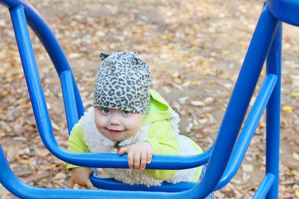 Schattig meisje in vest klimt op blauwe ladder op de speelplaats op — Stockfoto