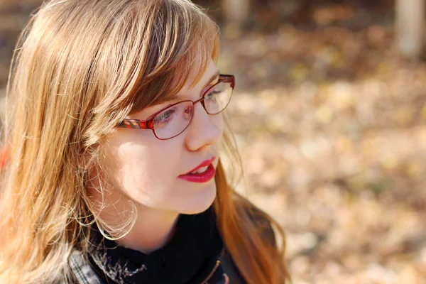 Jeune femme souriante dans des lunettes regarde loin à la journée ensoleillée, peu profonde — Photo