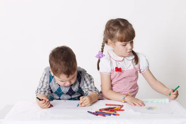 小男孩和女孩战平坐在桌旁的蜡笔 — 图库照片