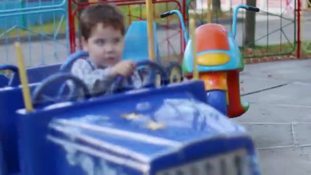 Happy little cute boy rides on carousel with cars, text on wall - wc — Stock Video