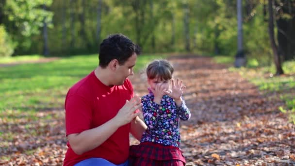 Kleines Mädchen und ihr Vater winken und spielen im sonnigen Herbstpark — Stockvideo