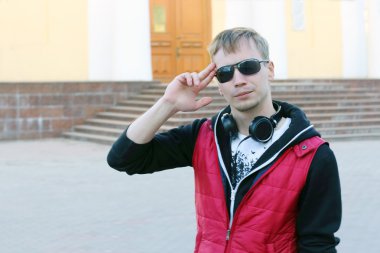 Genç adam kırmızı yelek ve kulaklık selamlıyor Street: s