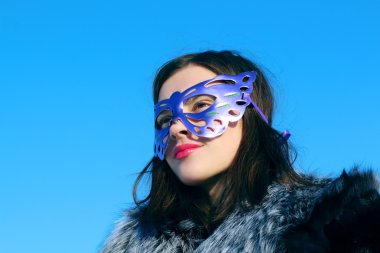 Güzel kız kürk manto ve maske uzakta güneşli kış d görünüyor