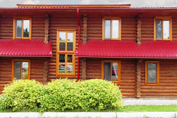 Facade of wooden building with slate roof and windowsand green b — Stock Photo, Image