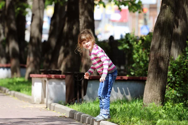 Oldukça mutlu kız çizgili süveter ve kaldırım kenarında ayakta kot — Stok fotoğraf