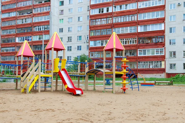 Bunter Spielplatz im Sand neben Wohnhochhaus — Stockfoto
