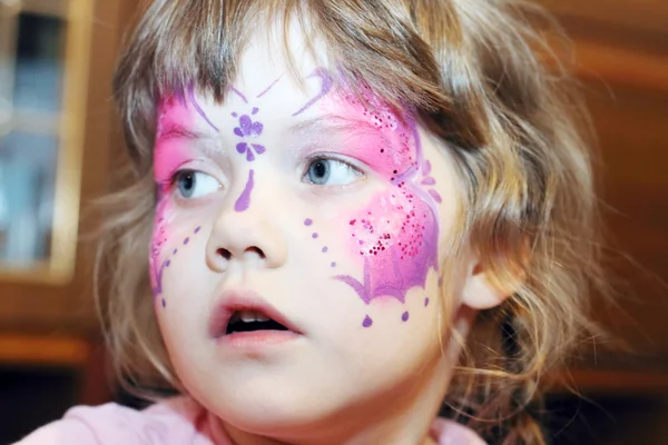 Felice bambina con farfalla viola nella foto sul viso guarda un — Foto Stock