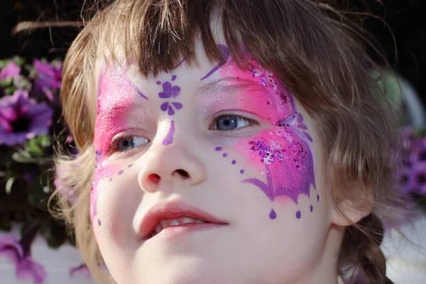 Happy little girl with pictured purple butterfly on face with ti — Stock Photo, Image