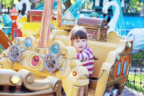 Pretty smiling little girl ride on carousel pirate ship in summe — Stock Photo, Image