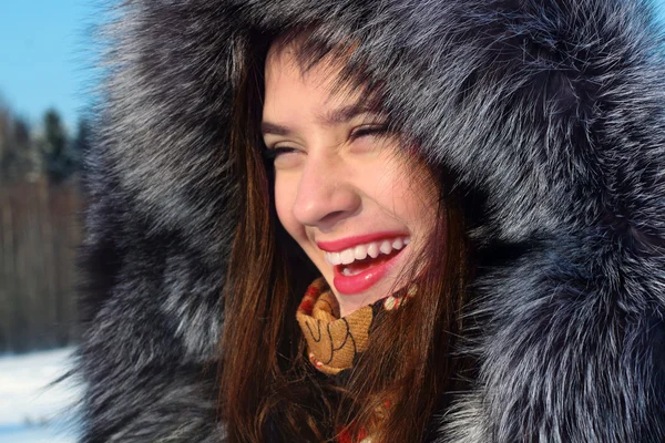 Belle fille en manteau de fourrure avec capuche rit en plein air dans la victoire ensoleillée — Photo