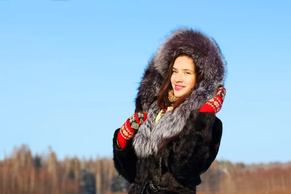 Menina bonita em casaco de pele com capuz sorri ao ar livre em vitória ensolarada — Fotografia de Stock