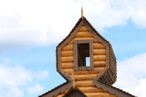 Partie du toit de la maison en bois rond avec fenêtre sur fond bleu ciel — Photo