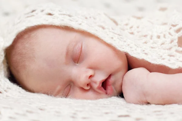 Peaceful baby lying on bed with soft white knitted blanket while — Stock Photo, Image