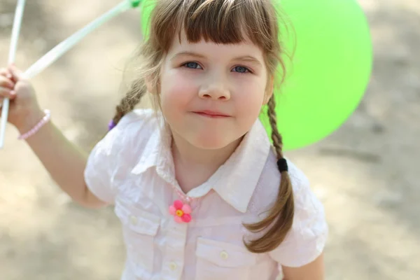 Pretty happy little girl holds green balloons at sunny day outdo — Stock Photo, Image