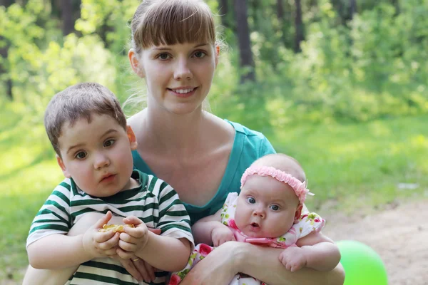 Happy young mother with two surprised kids in summer sunny fores — Stock Photo, Image