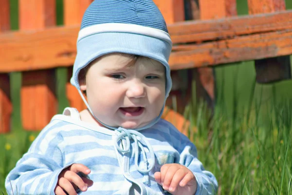 Primo piano di carino bambino in abito a righe blu e cappello seduto — Foto Stock