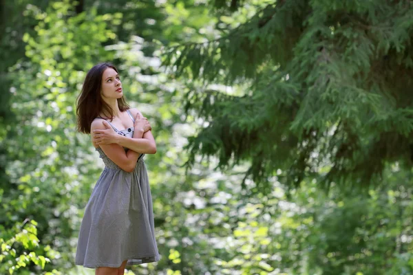 Hermosa chica en vestido con el pelo largo de pie en el bosque en la oposición — Foto de Stock