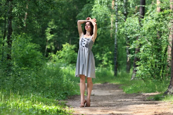 Beautiful girl in dress with long hair, walking on footpath in w — Stock Photo, Image