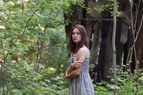 Beautiful girl in dress stands and looks aside hugging himself — Stock Photo, Image