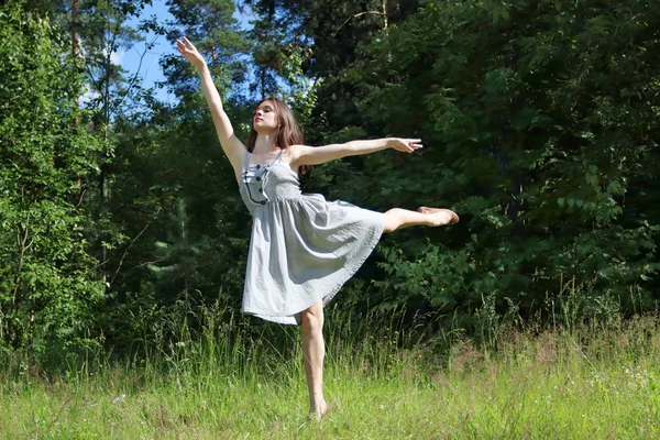 Hermosa chica en vestido en pose de golondrinas en claro en los bosques — Foto de Stock
