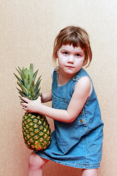 Mädchen im Jeanskleid hält große grüne Ananas in der Hand — Stockfoto