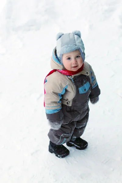 Ragazzino con indosso tuta calda sta sulla neve e sorride a wi — Foto Stock