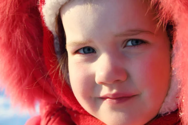 Dziewczynka w czerwonym ciepłe futro kaptur patrzy na aparat w zimie słoneczny — Zdjęcie stockowe