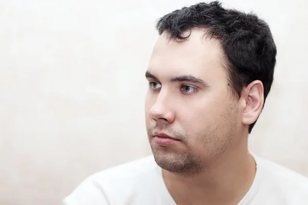 Portret van knappe ernstige man in wit t-shirt indoor close-up — Stockfoto