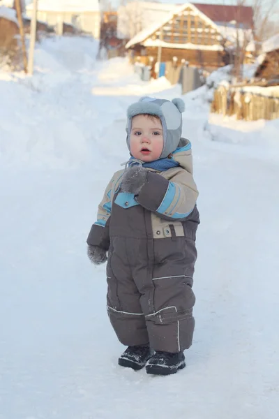 Kleiner Junge im warmen Overall steht im Winter im Schnee — Stockfoto