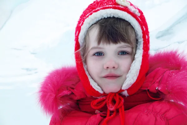 Piccola ragazza felice in rosso vestiti caldi guarda la fotocamera in inverno — Foto Stock