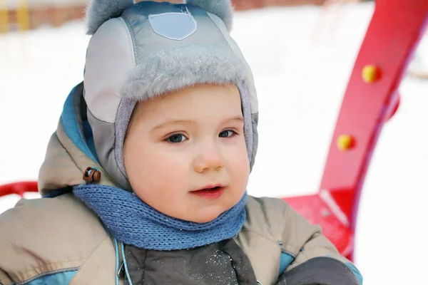 Liten pojke bär hatt och jumpsuit spela vid lekplatsen på vintern — Stockfoto