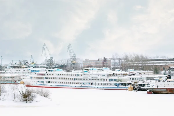Großes Touristenschiff und andere Schiffe auf zugefrorenem Fluss bei winterlichem Schnee — Stockfoto