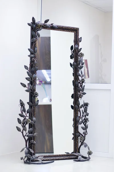 Gewrocht frame samengebonden met rozen met spiegel in witte kamer — Stockfoto