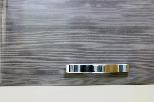 Λαμπρό χρώμιο Χειριστείτε σχετικά με καφέ ξύλινη πόρτα στο ντουλάπι. Κοντινό πλάνο — Φωτογραφία Αρχείου