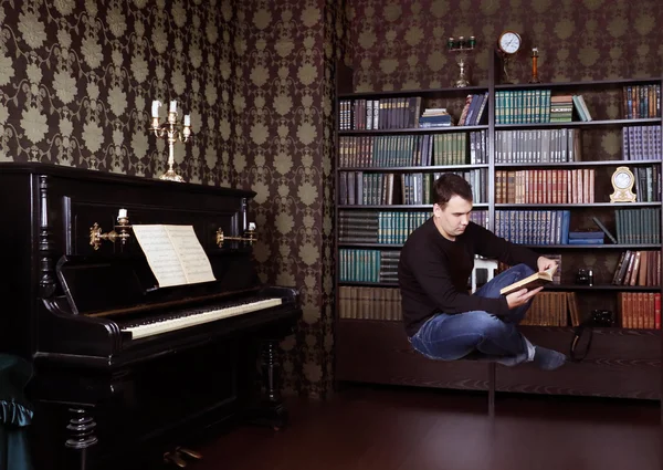 Hovering man reads book in room with shelves