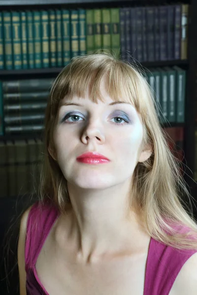 Молодая женщина сидит в комнате с книжными полками — стоковое фото