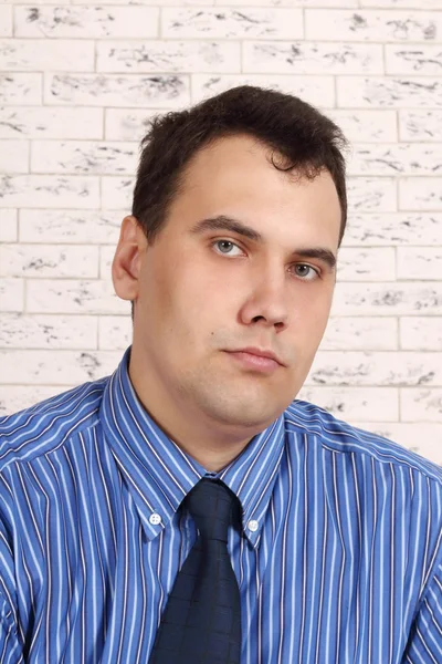 Beautiful young serious man looks at camera in room — Stock Photo, Image