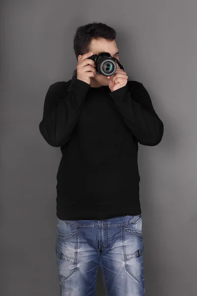 英俊的年轻男子，穿着牛仔裤与现代相机拍摄 — 图库照片