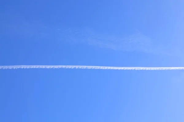 Long white trail in beautiful blue sky from engine flying plane — Stock Photo, Image